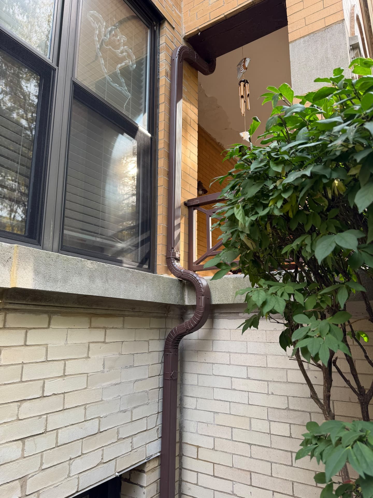 Porch ceiling water damage before, and the new exterior downspout after a gutter re-route at a Lake View condo complex (After)